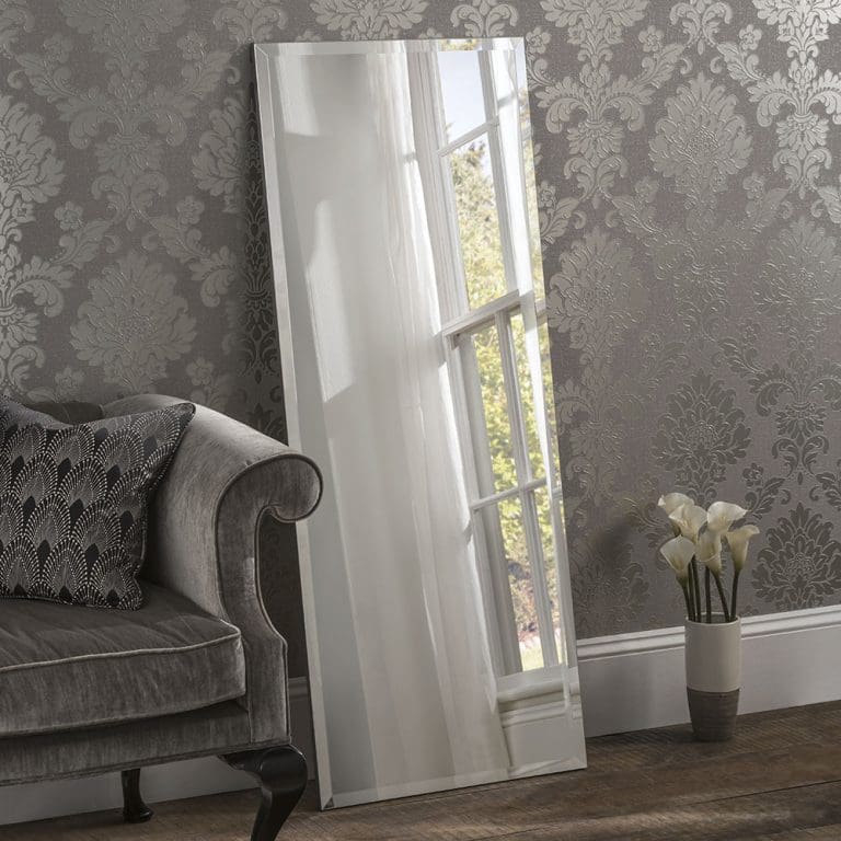 Bespoke Florence mirror. An all glass frameless mirror featuring a 25mm bevel edge. Leaning against a bedroom wall. Can be made to measure.