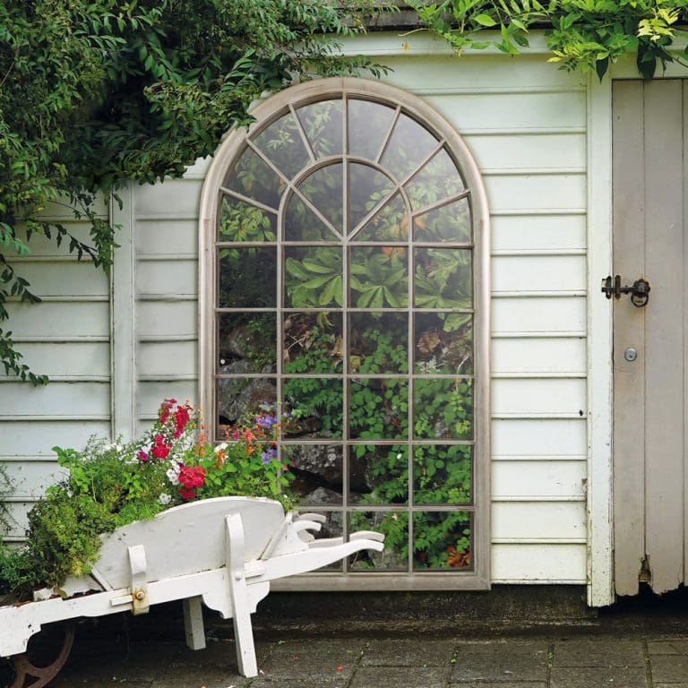 Large outdoor window mirror. Wall mounted on a garden shed. Reflecting the garden and patio. Are garden mirrors a fire risk?